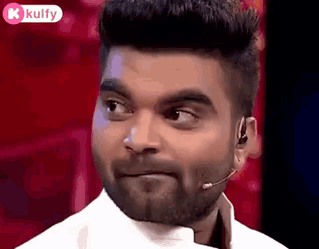 a man with a beard and a microphone on his ear is making a face .