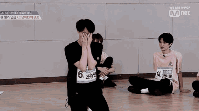 a group of young men are sitting on the floor with one wearing a tag that says ' 14 ' on it
