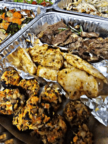 a variety of food in foil trays including stuffed mushrooms