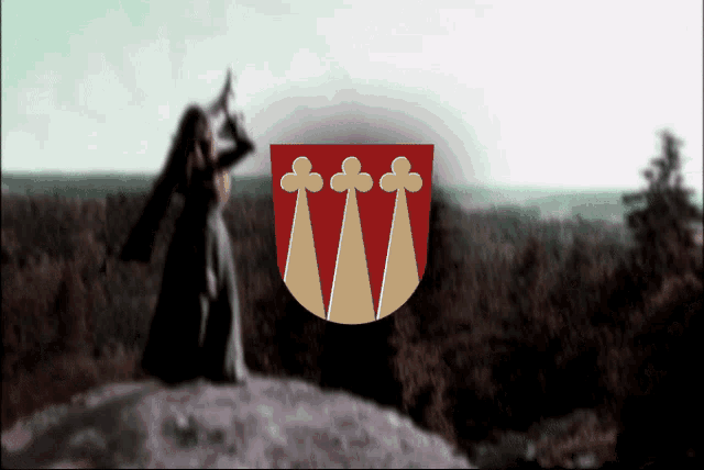a blurred image of a woman standing on a hill with a coat of arms in the foreground