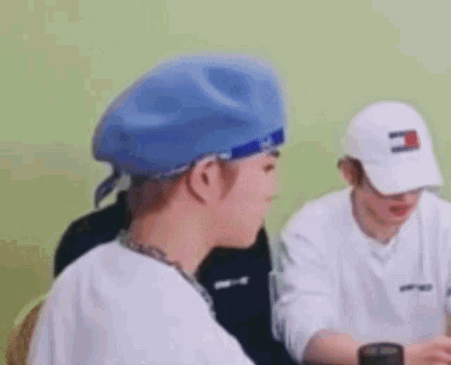 a man wearing a blue beret and a white hat is sitting at a table with another man .