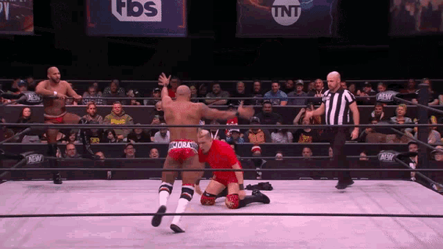 a wrestling ring with a tnt logo on the wall behind the referee