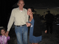 a man and a woman holding hands with a little girl in a purple dress