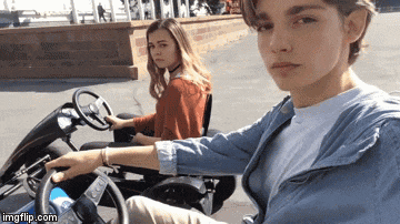 a man is driving a go kart with a girl behind him