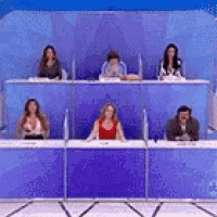 a group of people are sitting in front of a blue wall .
