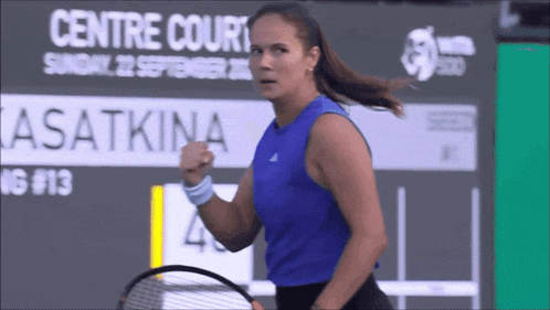 a woman in a blue tank top is holding a tennis racquet in front of a sign that says centre court