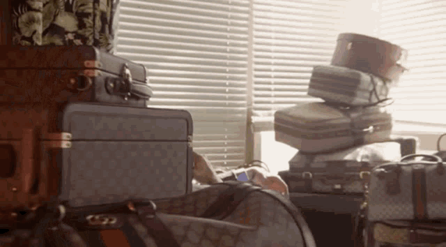 a stack of luggage including a gucci bag sits in front of a window