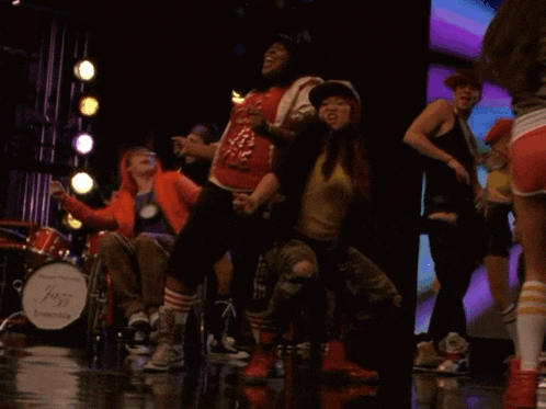 a man in a wheelchair is watching a group of people dancing on a stage