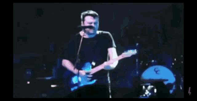 a blurry picture of a man playing a guitar with the number 4 on the bottom right