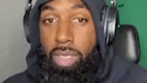 a man with a beard is wearing headphones and a hooded jacket .
