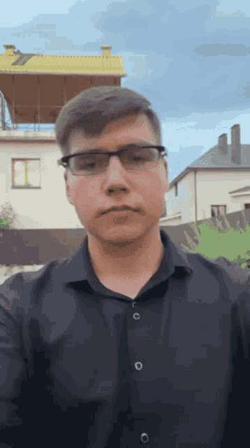 a man wearing glasses and a black shirt is taking a selfie