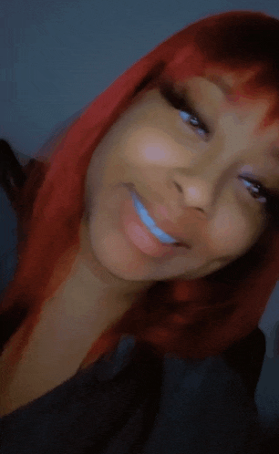 a woman with red hair is smiling and wearing a black shirt .