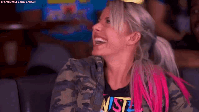 a woman with pink hair is laughing while sitting in a stadium .