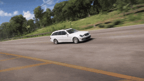 a white station wagon is driving down a road