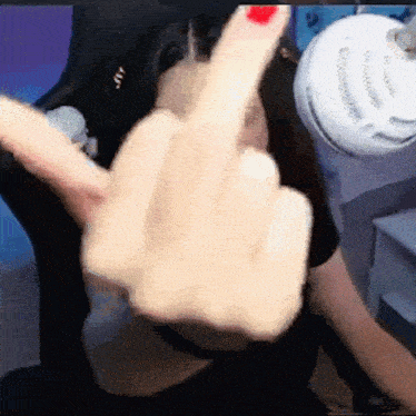 a woman with red nails is giving the middle finger while sitting in a chair .