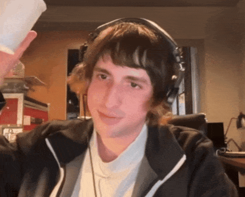 a man wearing headphones holds up a cup of coffee