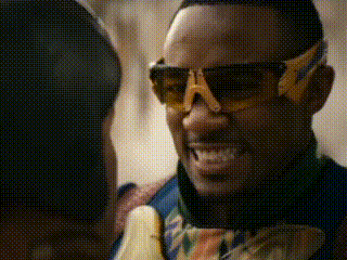 a man wearing sunglasses with the letter a on them is smiling while holding a banana .