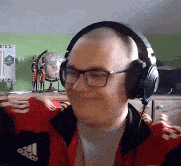 a man wearing headphones and a red adidas jacket is making a funny face .