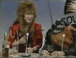 a man and a woman are sitting at a table with microphones and drinking .