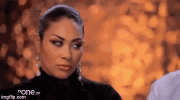a woman in a black turtleneck is looking at the camera with a serious look on her face .