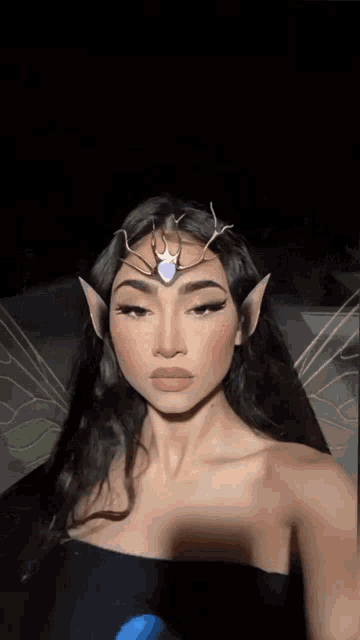 a woman is wearing a fairy costume and taking a selfie with a crown on her head .
