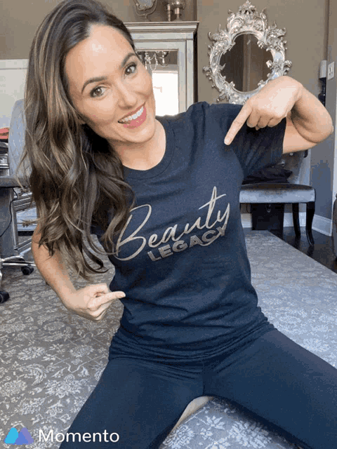 a woman wearing a black beauty legacy t-shirt points to her chest
