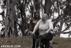 a man and a woman are riding a bike in a forest .