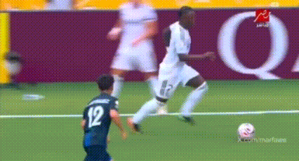 a soccer player wearing a number 12 jersey kicks the ball