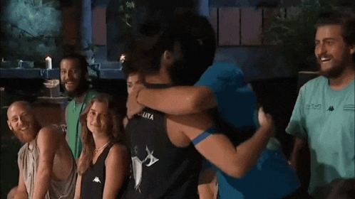 a group of people are hugging each other in a room .