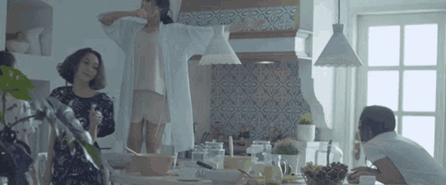 a group of women are dancing in a kitchen with a sign that says alo on it