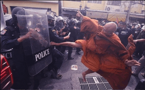 a group of police officers are standing around a man in an orange robe