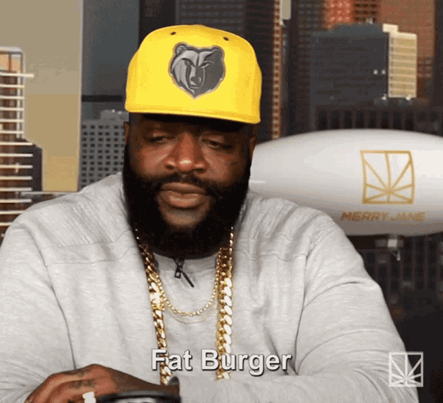 a man with a beard wearing a yellow hat that says fat burger
