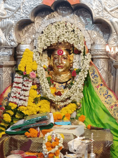 a statue of a woman with a red spot on her forehead is decorated with flowers