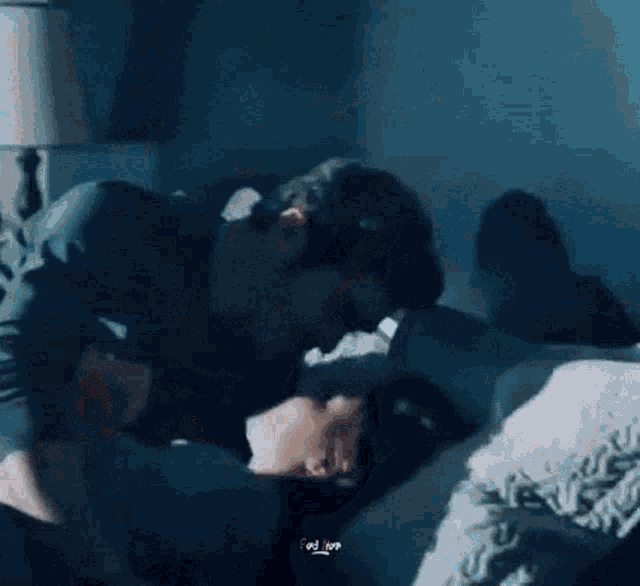 a man is kissing another man on the forehead while laying on a bed .
