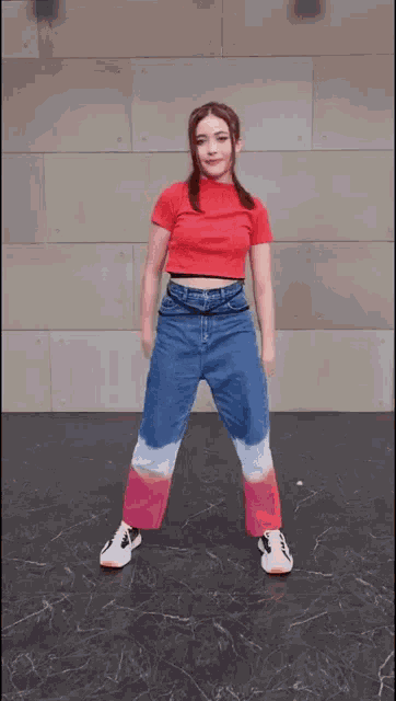 a woman in a red shirt and jeans is dancing
