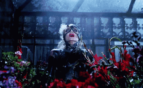 a woman in a cat woman costume is surrounded by flowers