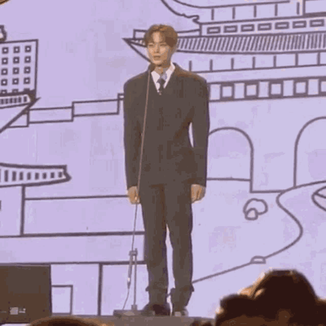 a man in a suit is standing in front of a microphone .