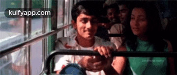 a man and a woman are sitting on a bus and looking out the window .