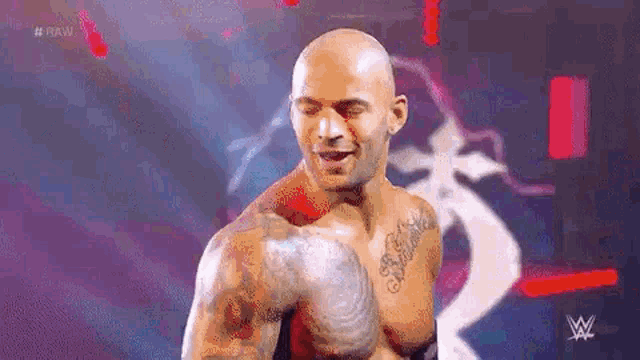 a bald man with a lot of tattoos on his arms and chest is standing on a stage .