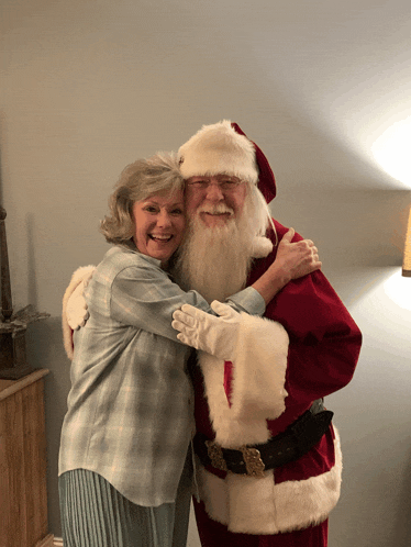 a man dressed as santa claus is hugging a woman