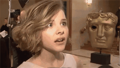 a woman is standing in front of a statue of a face .