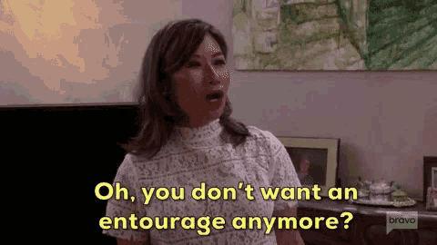 a woman is standing in a living room and saying oh you don 't want an entourage anymore