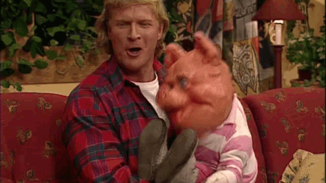 a man in a plaid shirt is holding a puppet on a red couch