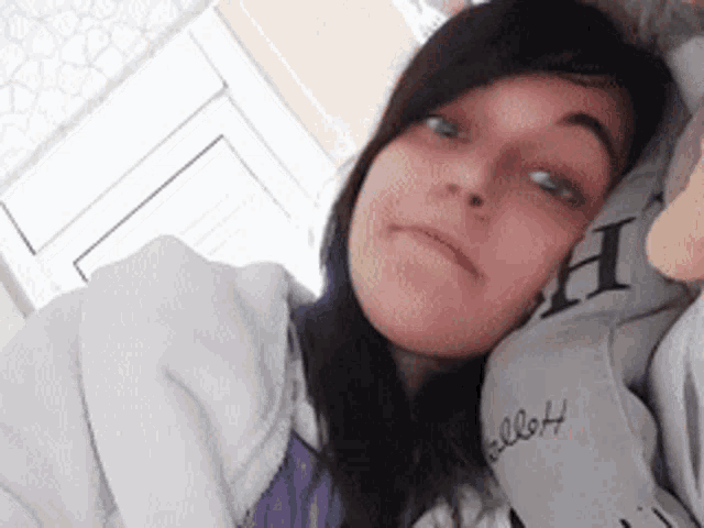a girl wearing a hello kitty sweatshirt is laying on a bed