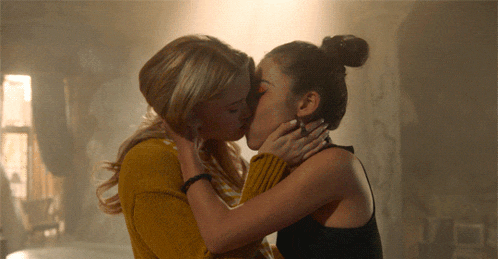 two women are kissing in a dark room and one has a ring on her finger