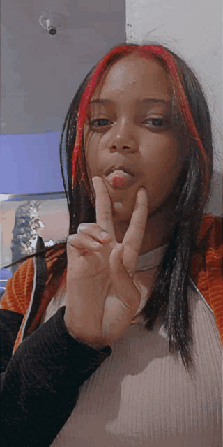 a woman with red hair is giving a peace sign