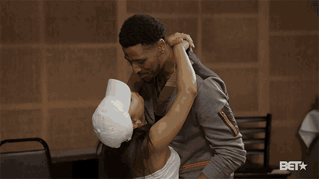 a man and woman are kissing in front of a bet sign