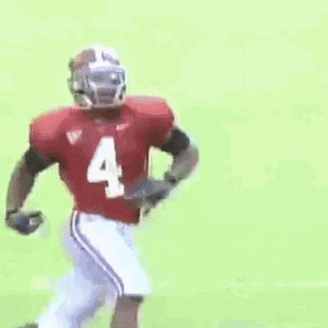 a football player wearing a red jersey with the number 4 is jumping in the air