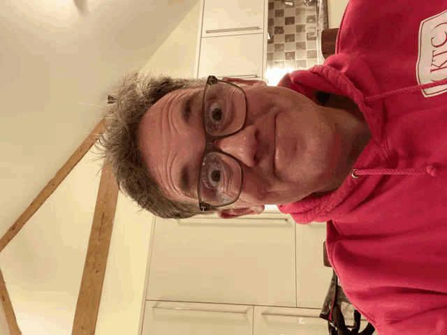 a man wearing glasses and a pink hoodie that says ' kitchen ' on it