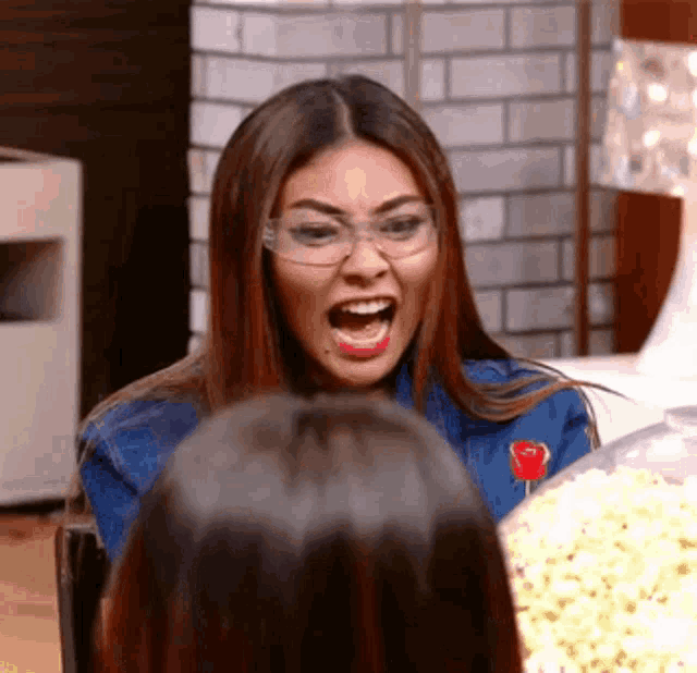 a woman wearing glasses is making a funny face with her mouth open